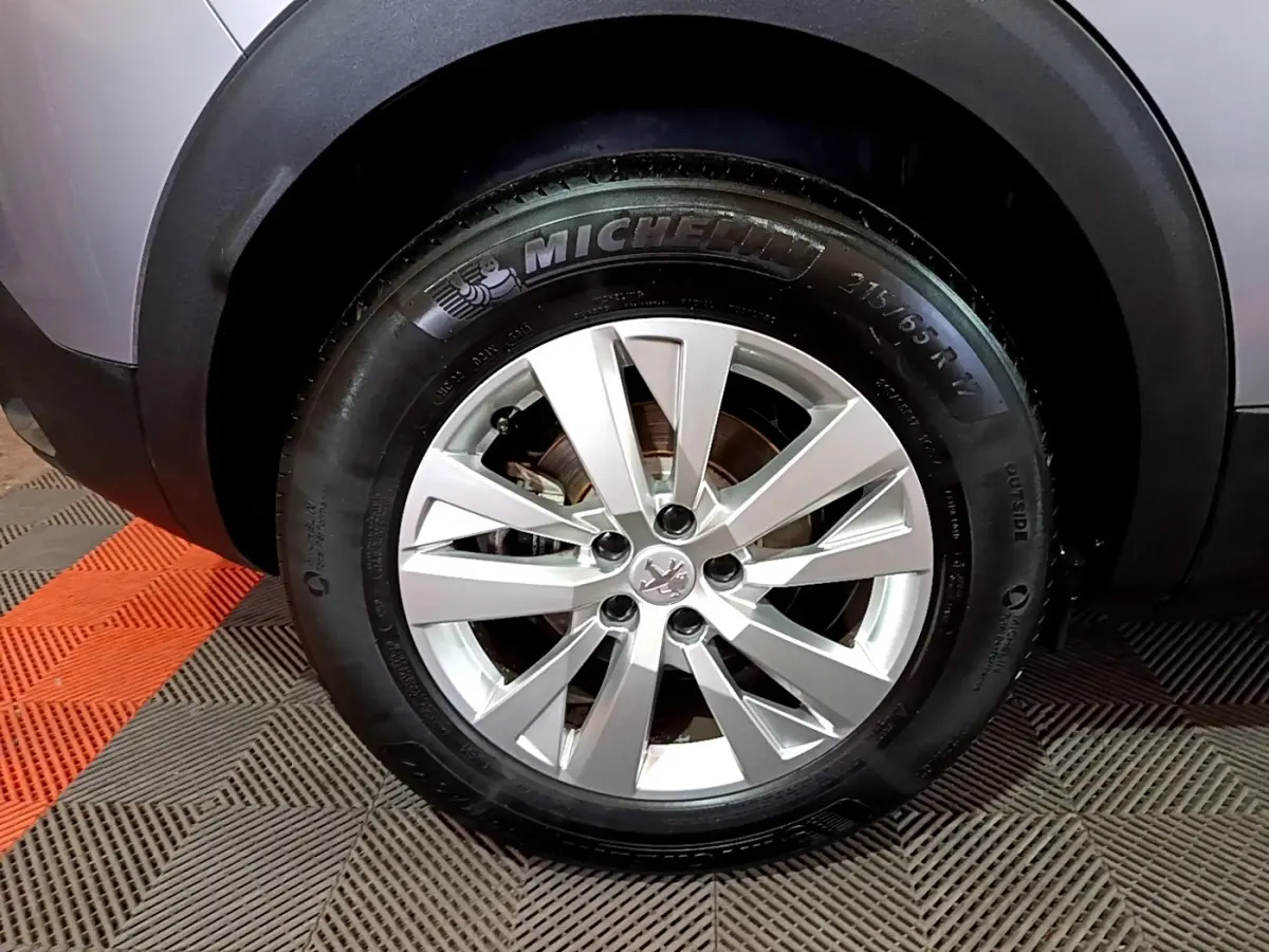 Gros plan sur la roue avant droite du Peugeot 3008 gris clair, avec jante alliage et pneu Michelin visible.