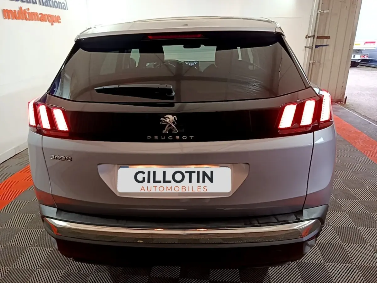 Vue arrière d’un Peugeot 3008 gris clair avec feux LED allumés dans un garage.