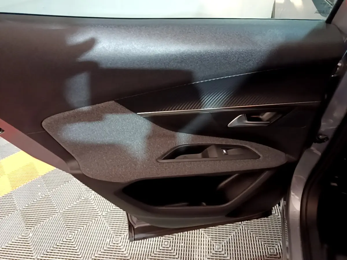 Vue intérieure du panneau de porte côté droit gris clair du Peugeot 3008, avec insert texturé et commande de lève-vitre.