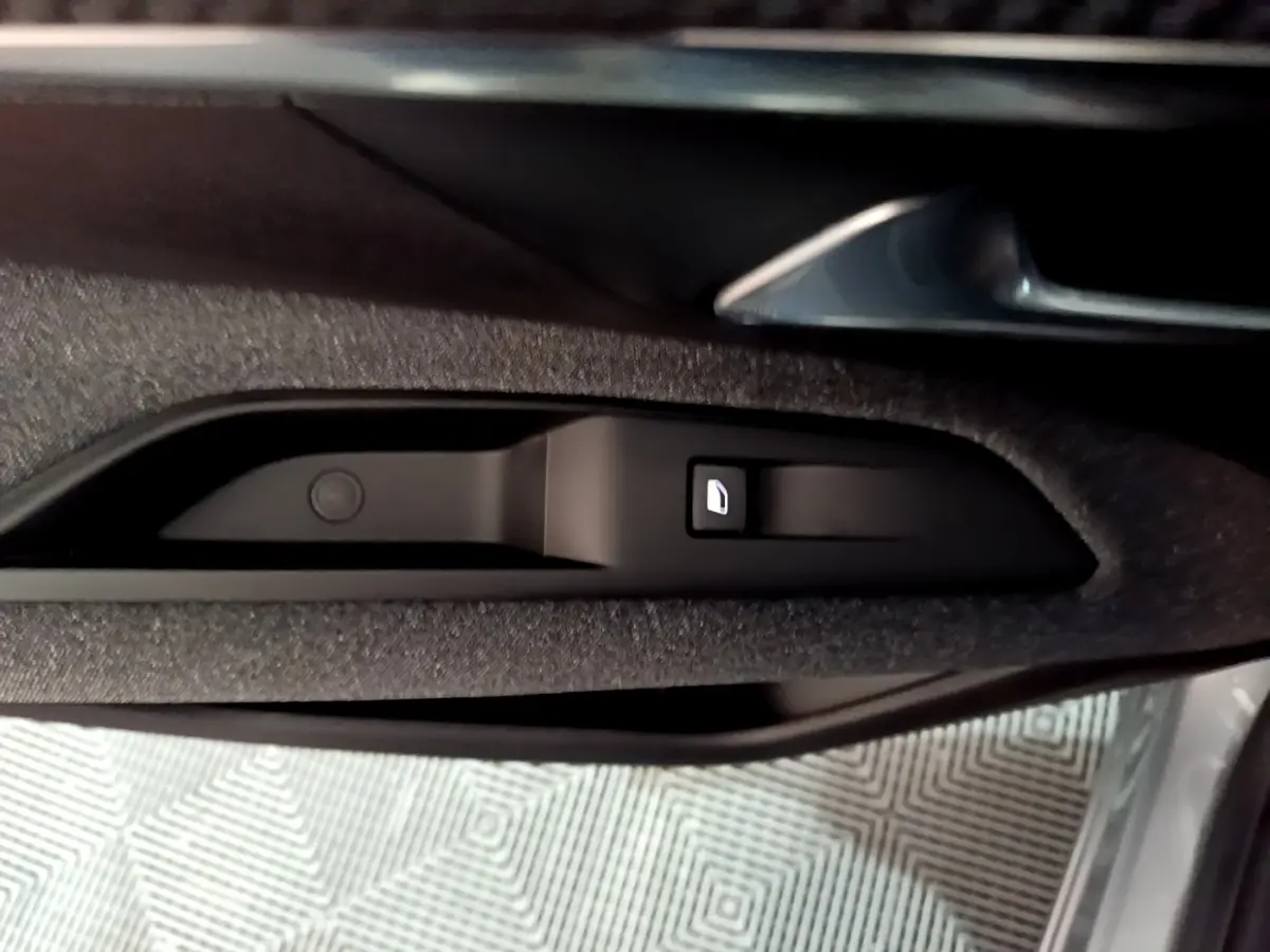 Gros plan sur la commande de verrouillage de porte intégrée à la garniture intérieure côté conducteur du Peugeot 3008 gris clair.