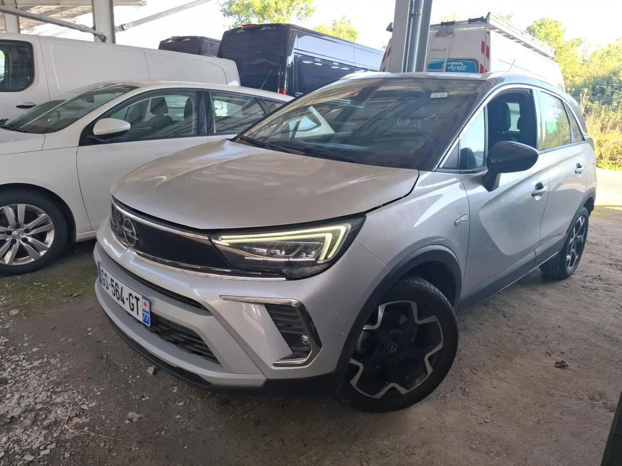 Vue 3/4 avant d’un Opel Crossland gris clair 2024 avec phares LED et jantes noires au design distinctif.