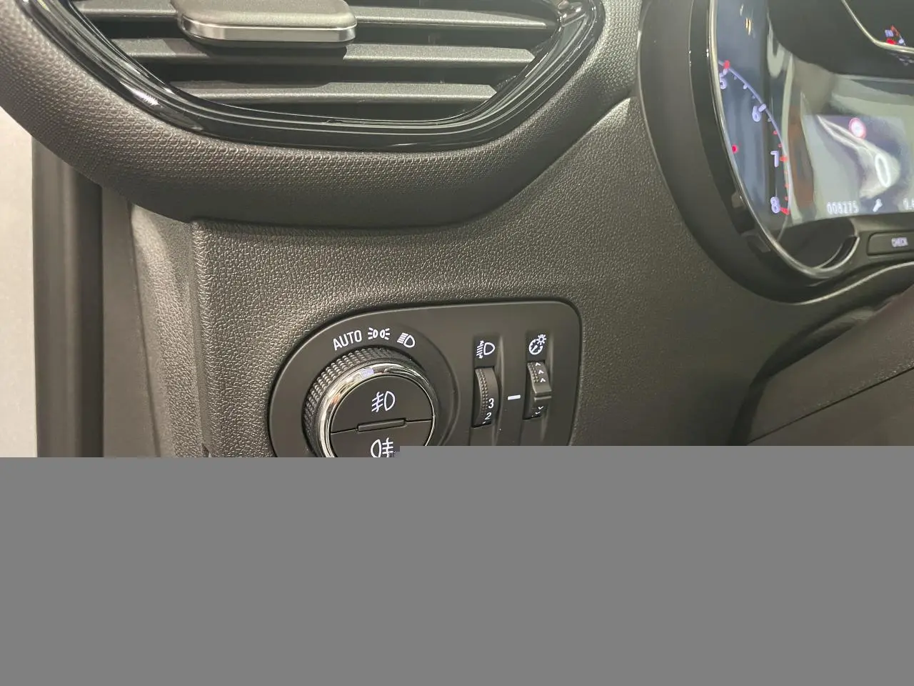 Détail du tableau de bord côté gauche de l’Opel Crossland gris clair 2024, avec commandes d’éclairage et compteur numérique partiel.