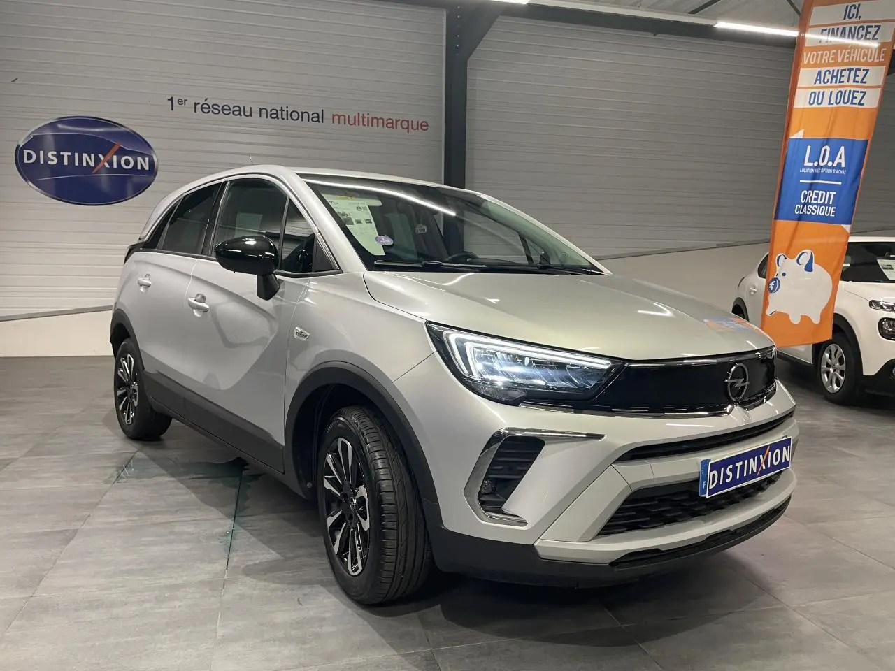 Opel Crossland gris clair en 3/4 avant droit, avec jantes alliage diamantées et calandre noire brillante.