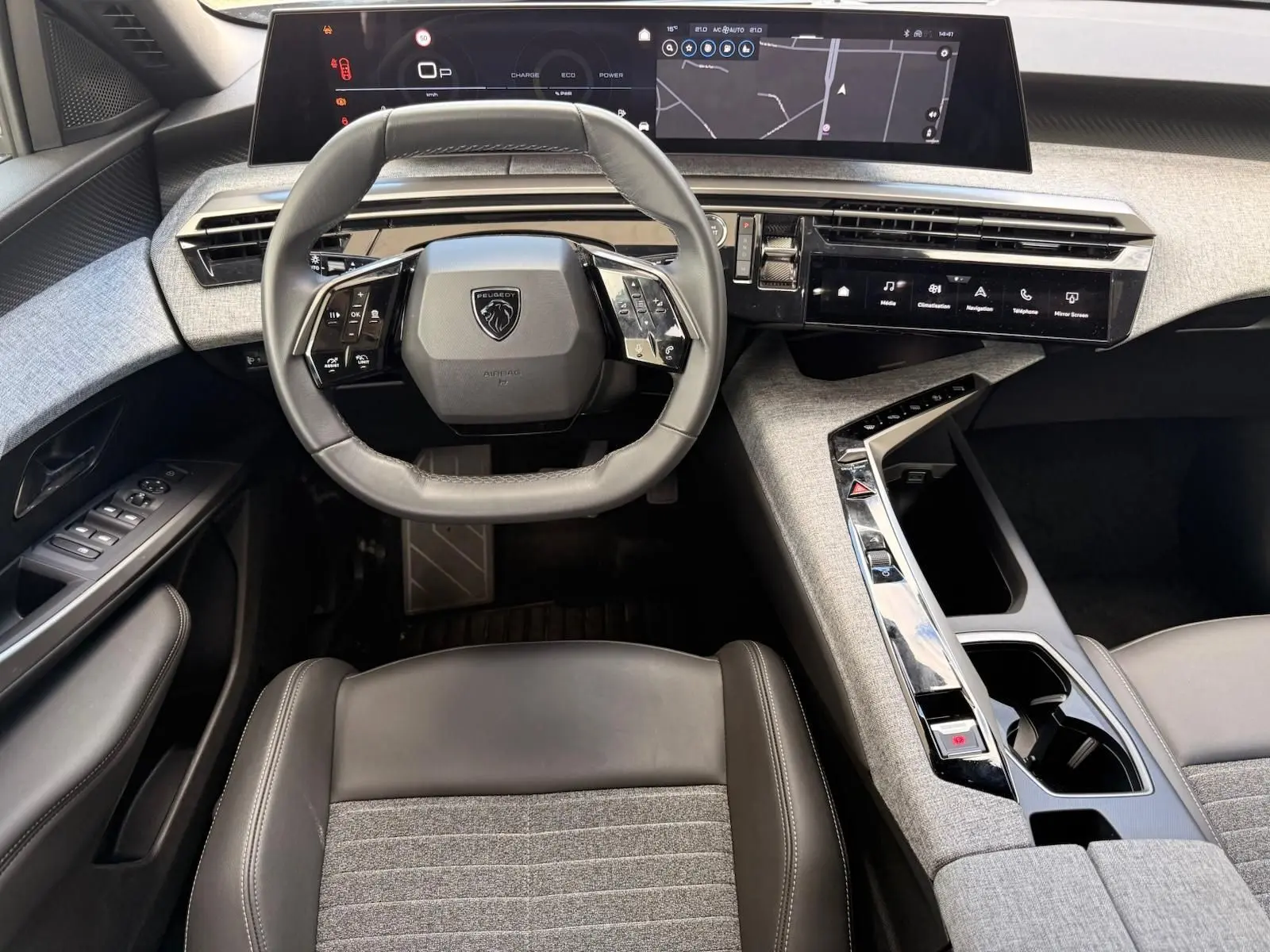 Vue intérieure frontale du tableau de bord gris artense du Peugeot 5008 Hybrid 145 avec écran tactile et volant compact multifonction.