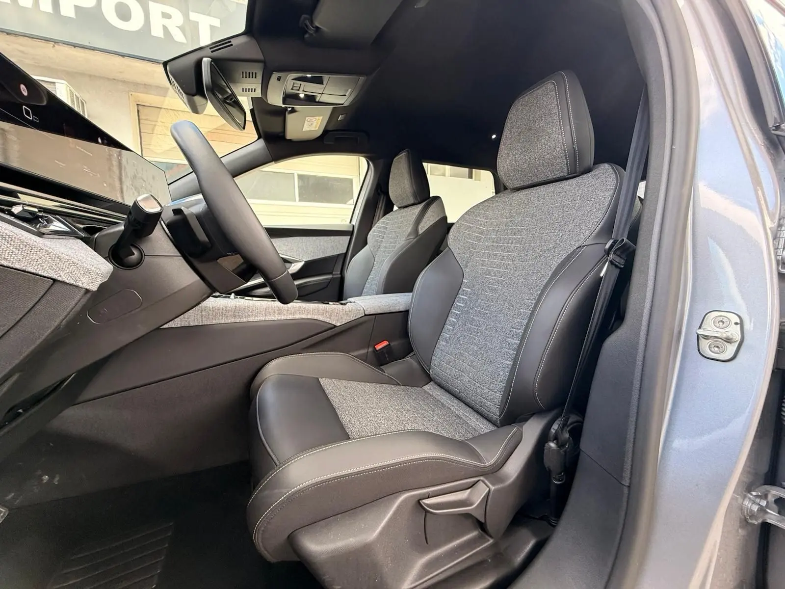 Vue intérieure côté conducteur du Peugeot 5008 Hybrid 145 en gris Artense, sièges tissu et cuir bi-matière visibles.