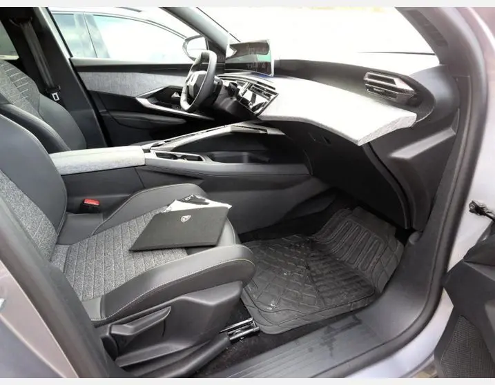 Vue 3/4 arrière droite du Peugeot 5008 Hybrid gris Artense avec jantes noires et vitres teintées, stationné en extérieur.