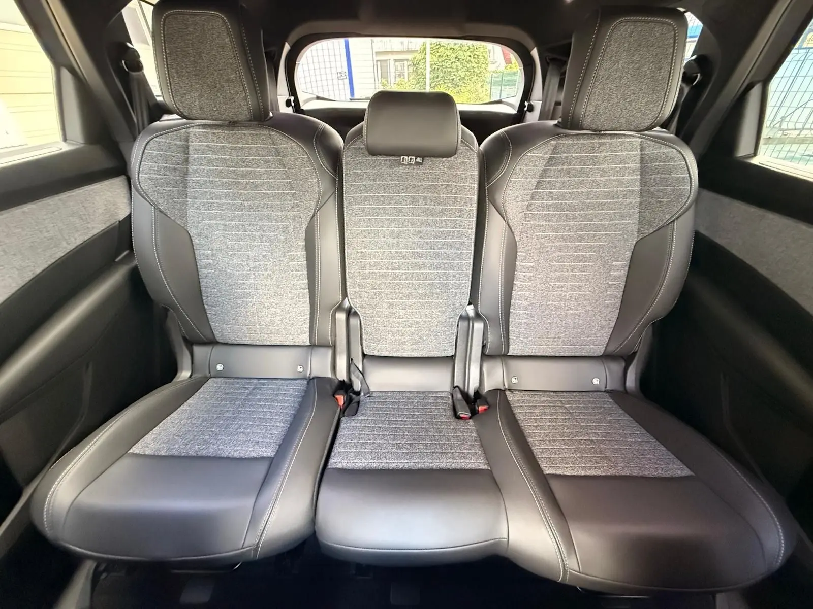 Vue intérieure arrière montrant les trois sièges gris et noirs du Peugeot 5008 Hybrid 2025 avec finition tissu et cuir.