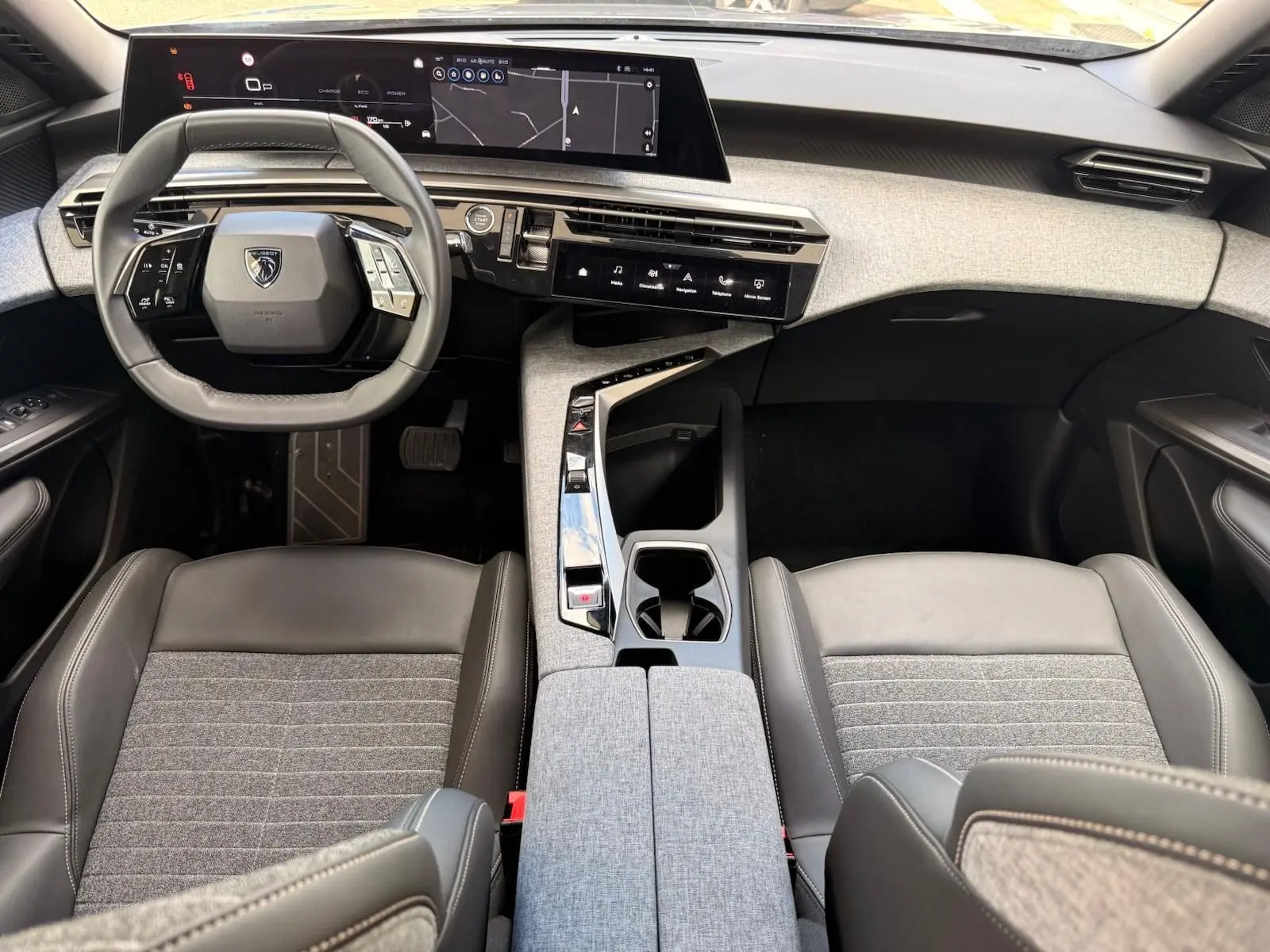 Vue intérieure frontale du poste de conduite du Peugeot 5008 Hybrid 145, avec volant compact et tableau de bord numérique.