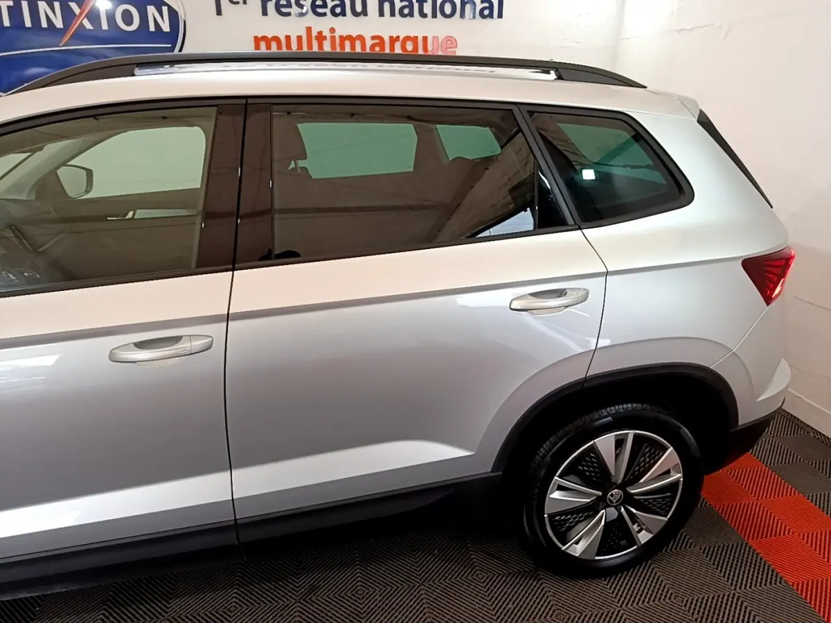Vue latérale droite d'un SKODA KAROQ gris clair, mettant en valeur les jantes alliage et les vitres teintées.