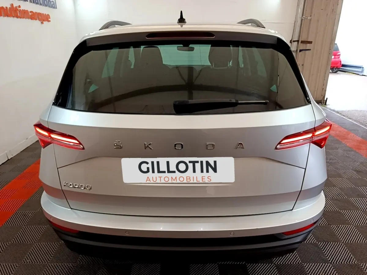 Vue arrière d’un Skoda Karoq gris clair 2022 avec feux LED allumés et logo ŠKODA bien visible.