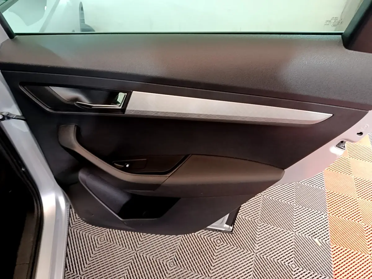 Vue intérieure de la porte arrière gauche gris clair du Skoda Karoq 2022 avec insert décoratif argenté et poignée noire.
