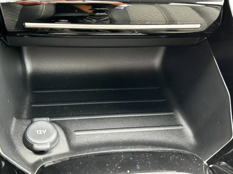 Prise 12V en gros plan dans le rangement central avant de la Peugeot 208 1.2 PureTech 2024, finition Allure