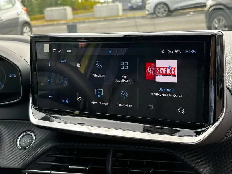 Écran tactile central de la Peugeot 208 2024 affichant l'interface multimédia avec radio Skyrock, vue intérieure frontale.