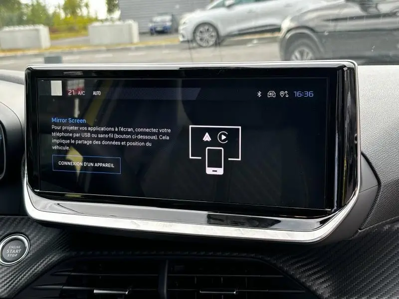 Écran tactile central allumé dans l'habitacle d'une Peugeot 208 2024, finition Allure, avec bouton start/stop visible.