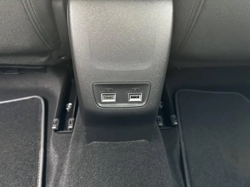 Vue rapprochée des ports USB arrière intégrés à la console centrale noire du Peugeot 208 2024.