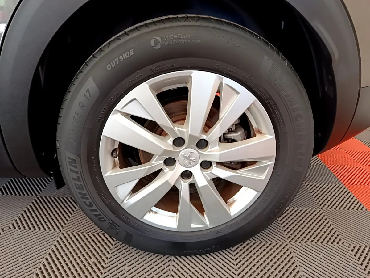 Gros plan sur la roue avant droite du Peugeot 3008 gris foncé, avec jante alliage et pneu Michelin visible.