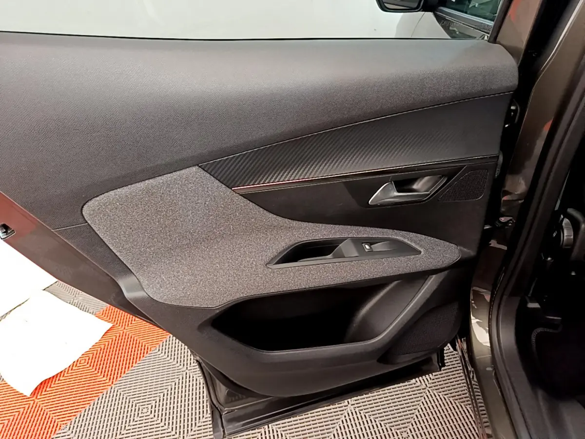 Vue intérieure de la porte arrière droite du Peugeot 3008 gris foncé, montrant les commandes de fenêtre et le revêtement textile.
