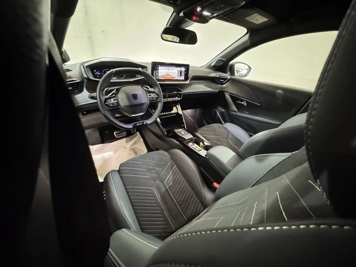 Intérieur de la Peugeot 208 Hybrid 136 eDCS6 GT vu côté conducteur, sièges noirs et tableau de bord numérique.