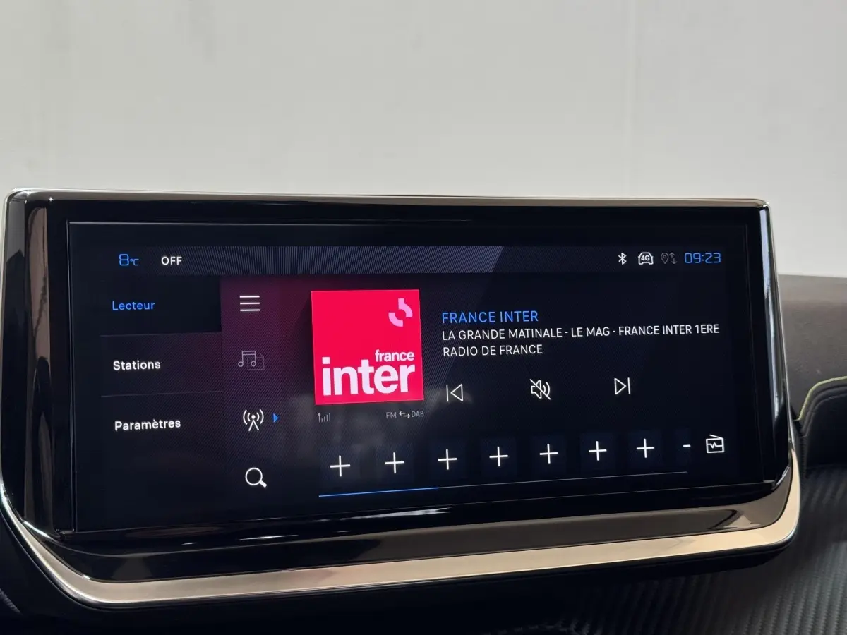Écran tactile central de la Peugeot 208 Hybrid gris clair affichant la radio France Inter en intérieur.