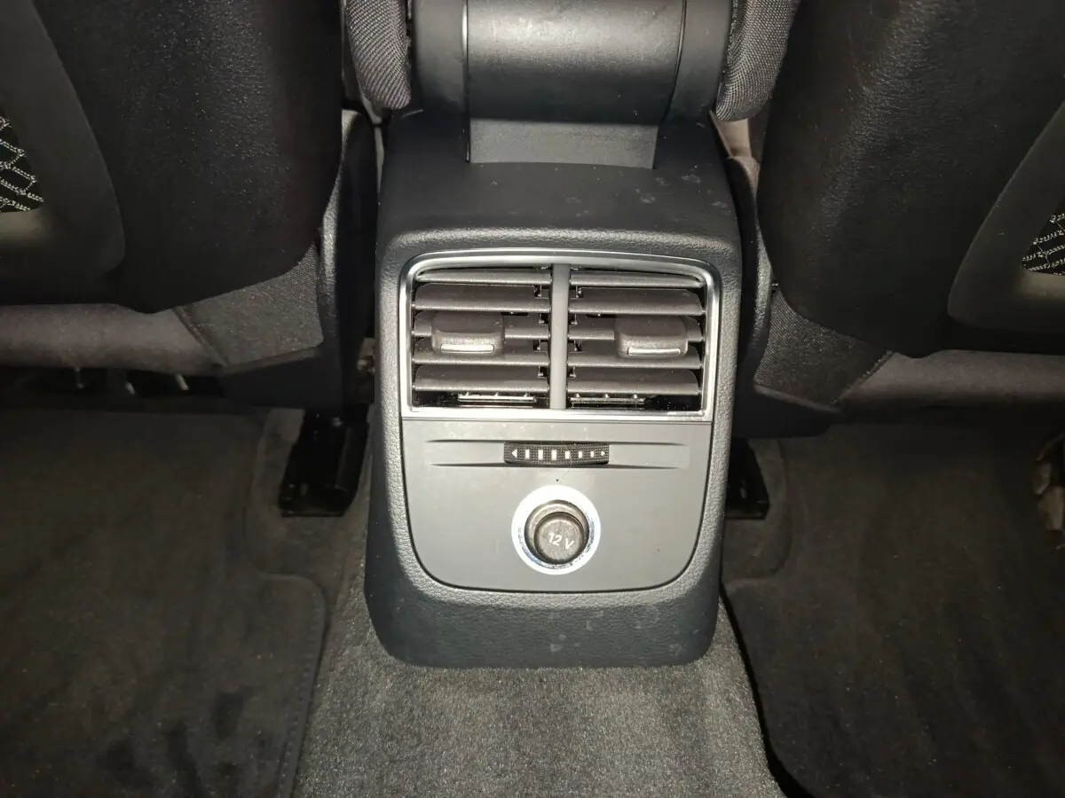 Vue rapprochée de la console centrale arrière noire avec bouches d’aération et prise 12V dans l’Audi A3 blanche 2020.