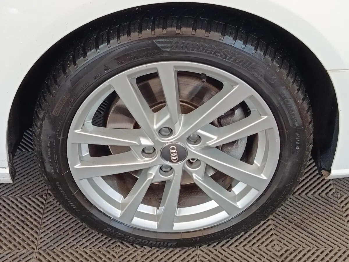 Gros plan sur la roue avant droite argentée d'une Audi A3 blanche, mettant en valeur la jante en alliage et le pneu Bridgestone.