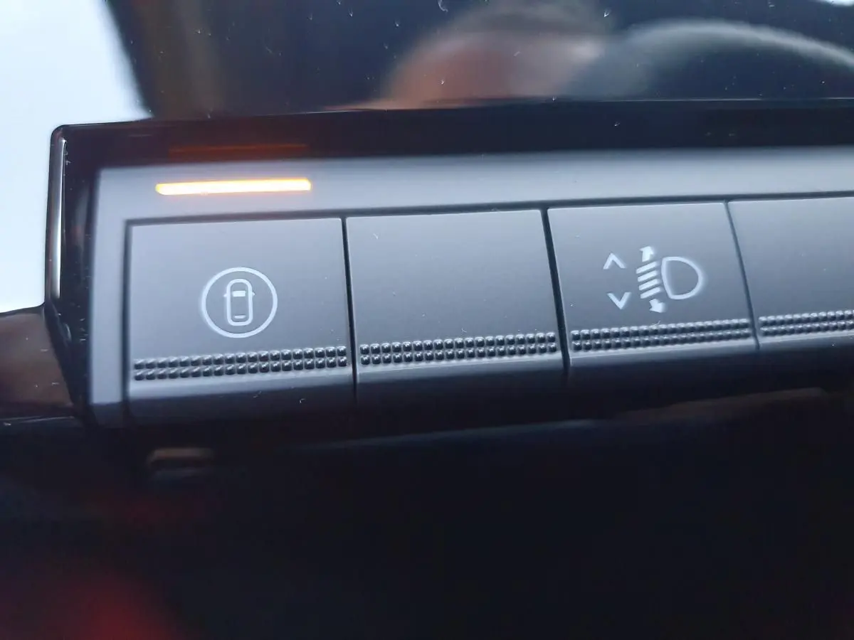 Gros plan sur les boutons de commande intérieurs de la Renault R5 E-TECH jaune Pop, avec témoin lumineux orange allumé.