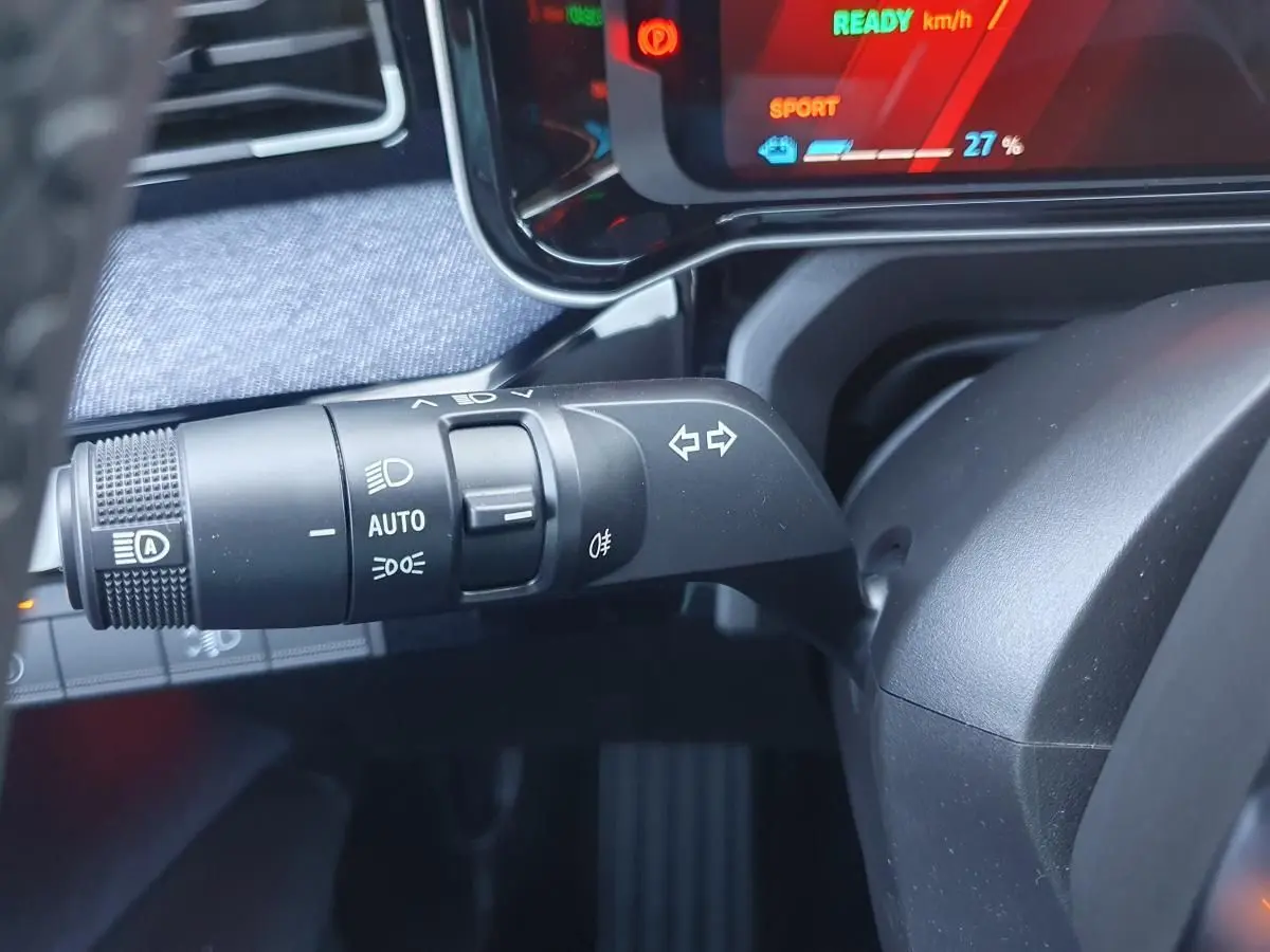 Gros plan sur la commande des clignotants et phares de la Renault R5 E-TECH 2026, tableau de bord numérique en arrière-plan.