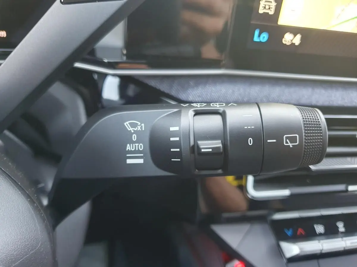Gros plan sur la commande des essuie-glaces dans l’habitacle de la Renault R5 E-TECH jaune Pop, avec écran tactile en arrière-plan.