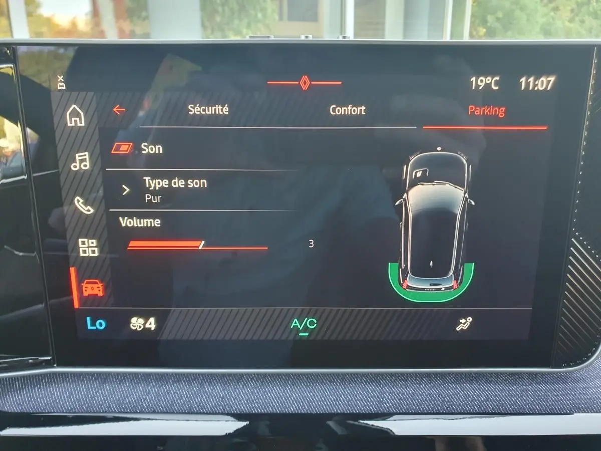 Écran tactile central de la Renault R5 E-Tech 2026 affichant l’aide au stationnement avec vue aérienne du véhicule.