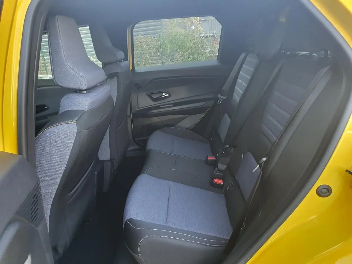 Vue intérieure arrière côté droit de la Renault R5 E-TECH jaune Pop, montrant les sièges arrière en tissu bicolore gris et noir.