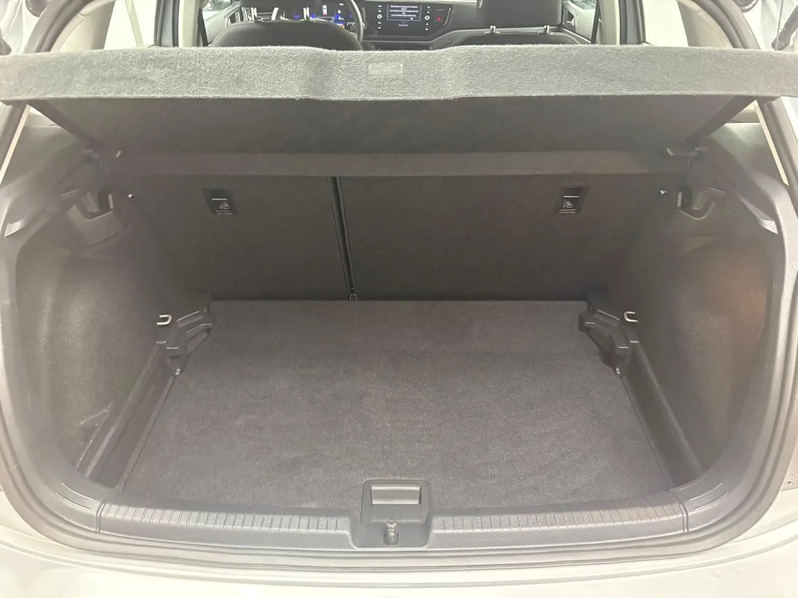 Vue intérieure du coffre spacieux et propre d'une Volkswagen Polo 2024 en Reflet d'argent, avec banquette arrière visible.