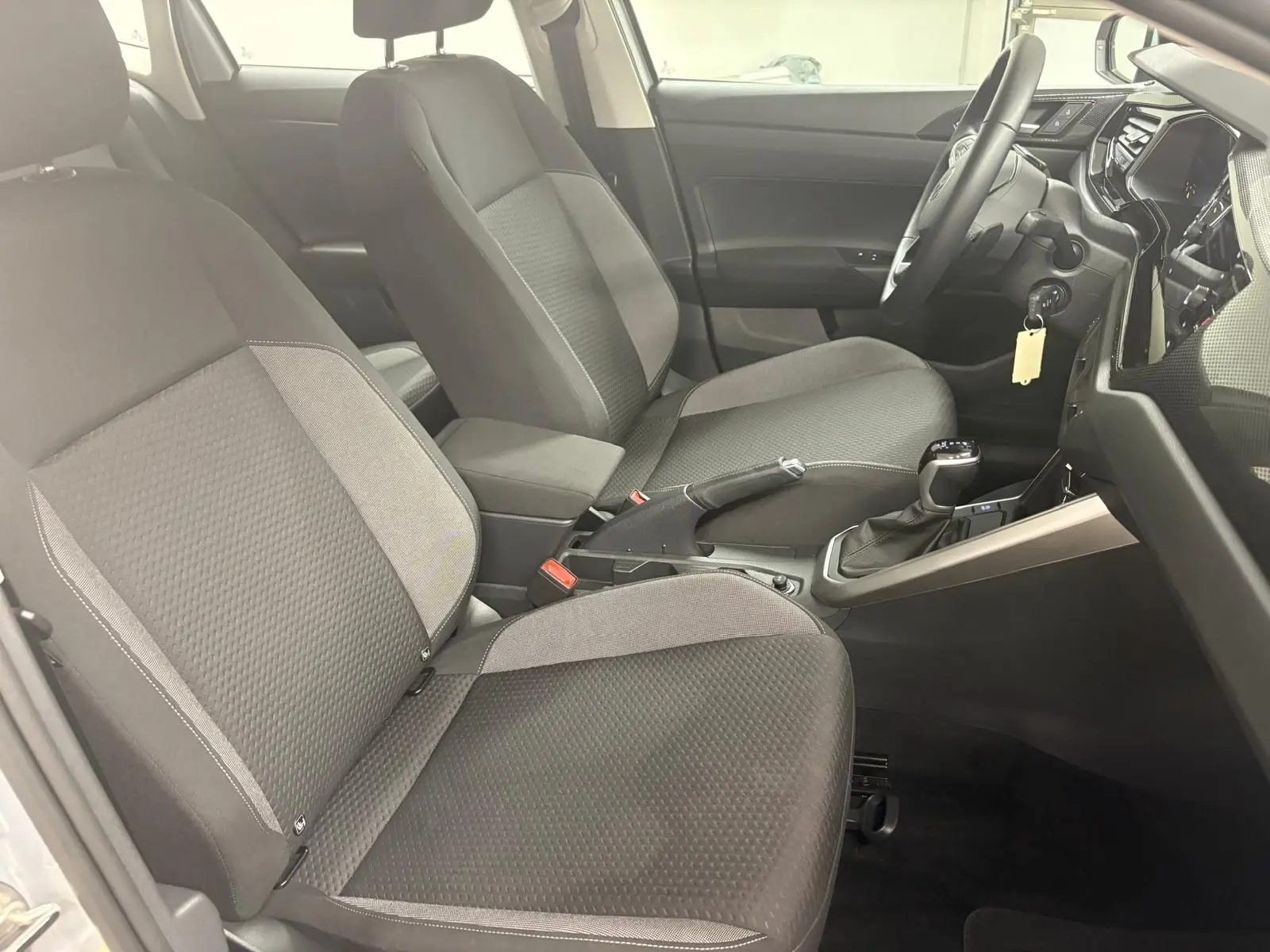 Vue intérieure côté conducteur de la Volkswagen Polo 2024 avec sièges tissu gris et console centrale noire.