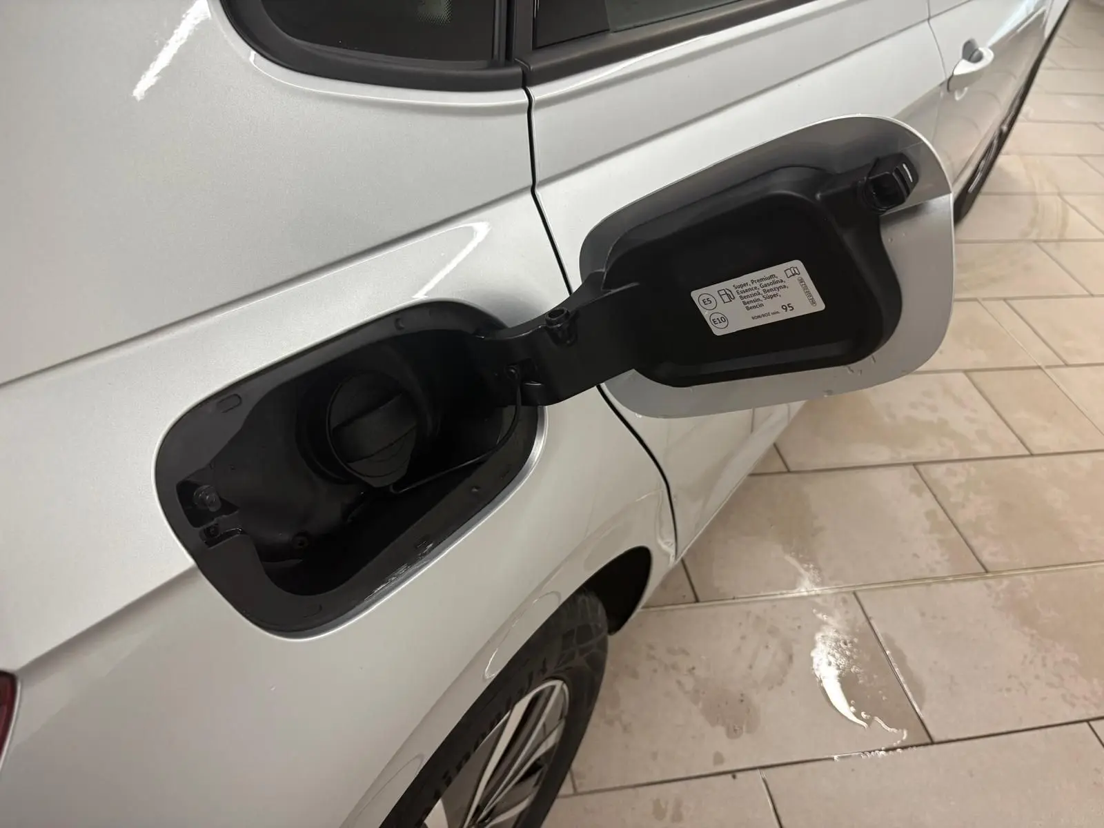 Vue rapprochée du côté gauche arrière d'une Volkswagen Polo 2024 argent métallisé avec trappe à carburant ouverte.