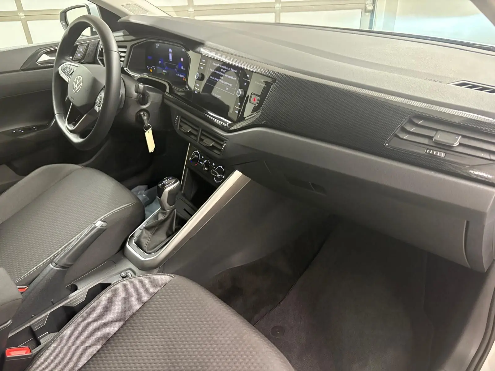 Intérieur avant droit de la Volkswagen Polo 2024 avec tableau de bord moderne et boîte automatique visible.