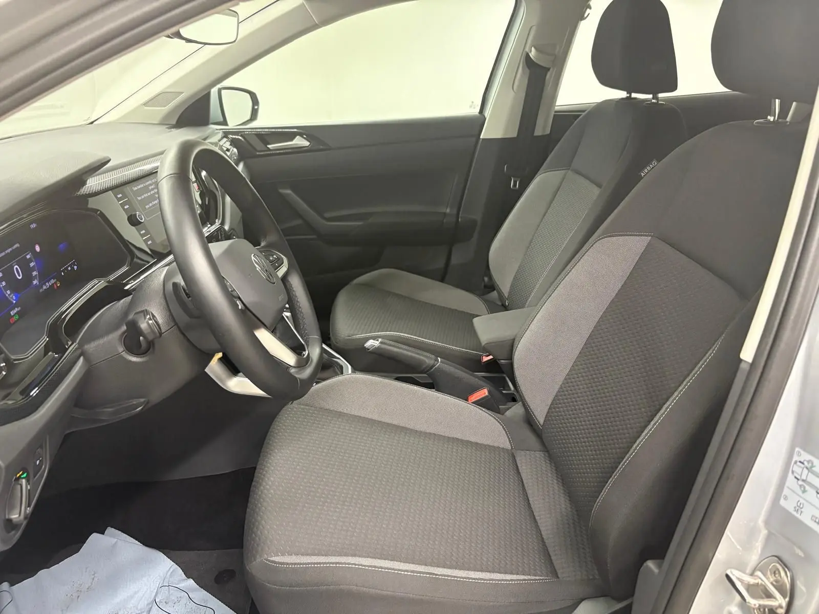 Intérieur avant droit de la Volkswagen Polo 2024 avec sièges gris et tableau de bord digital visible.