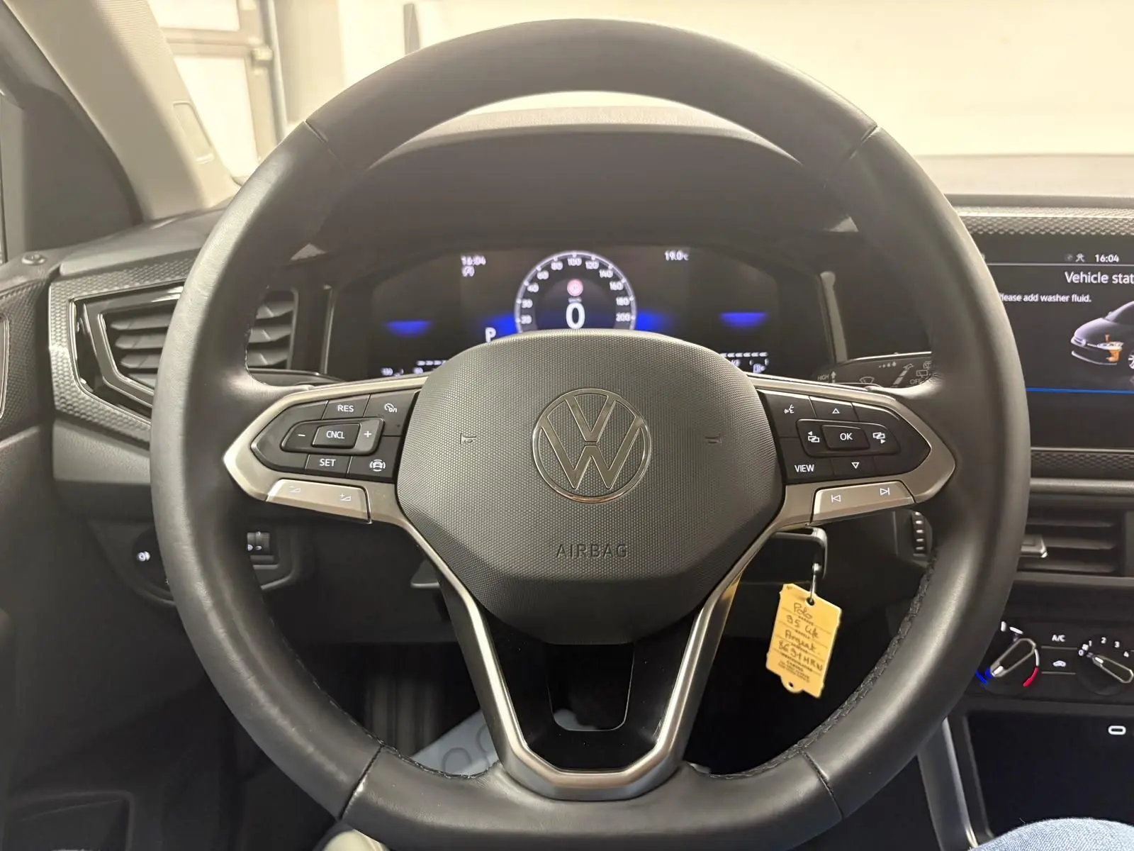 Vue rapprochée du volant multifonction noir d'une Volkswagen Polo 2024 avec tableau de bord digital allumé.
