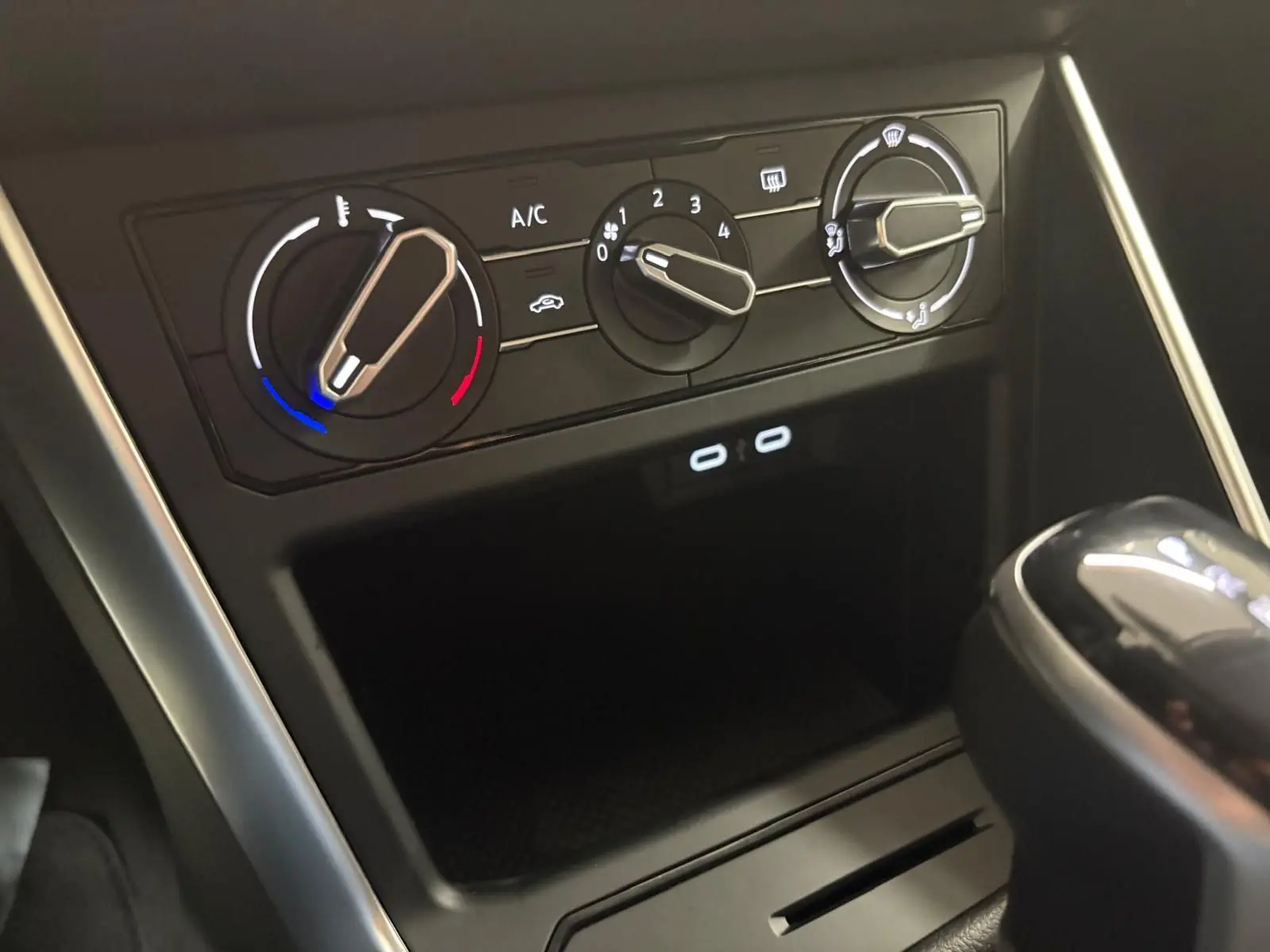 Gros plan sur les commandes de climatisation et la console centrale noire d'une Volkswagen Polo 2024, boîte auto.