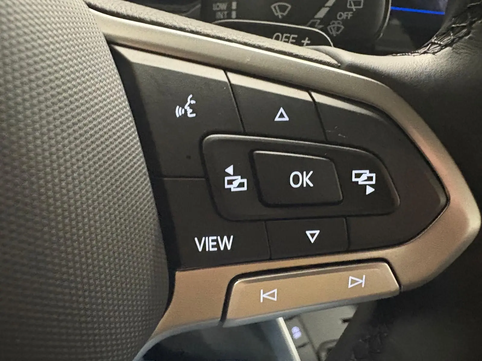 Gros plan sur les commandes au volant côté gauche du Volkswagen Polo 2024 en finition Life, avec boutons noirs et cadre argenté.