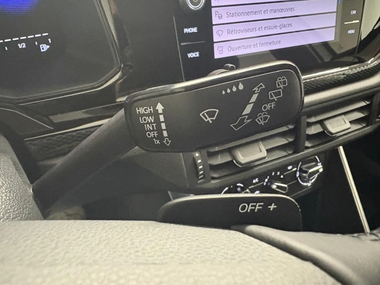 Gros plan sur la commande d'essuie-glace du Volkswagen Polo 2024, intérieur noir avec écran tactile affichant les réglages.