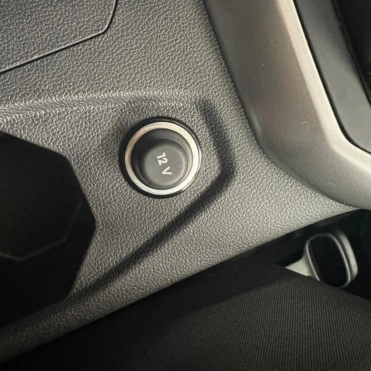 Prise 12V en gros plan sur la console centrale noire du Volkswagen Polo 2024 finition Life.