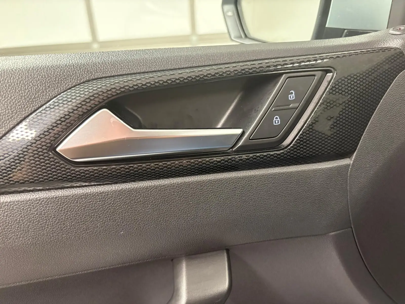 Poignée intérieure côté droit de la Volkswagen Polo 2024 avec finition noire texturée et boutons de verrouillage.