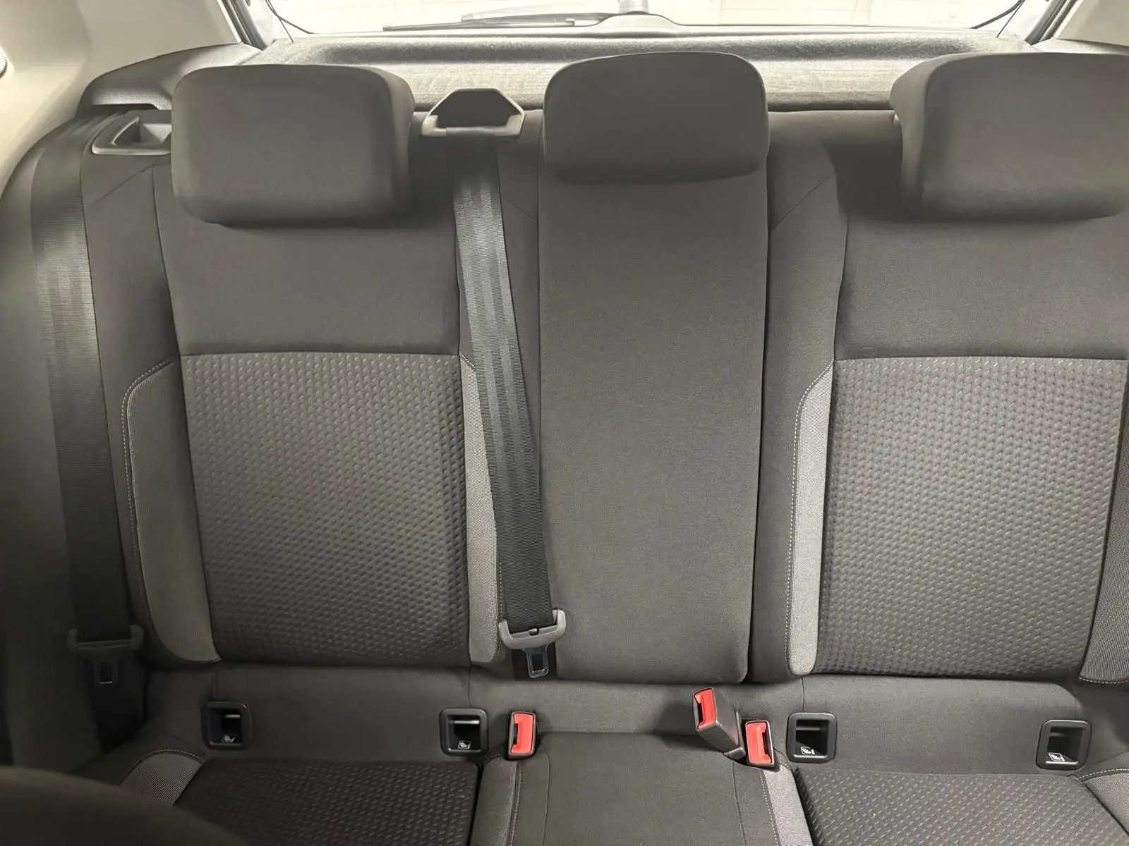 Vue arrière des sièges arrière en tissu gris foncé de la Volkswagen Polo 2024, avec ceintures et appuie-têtes visibles.