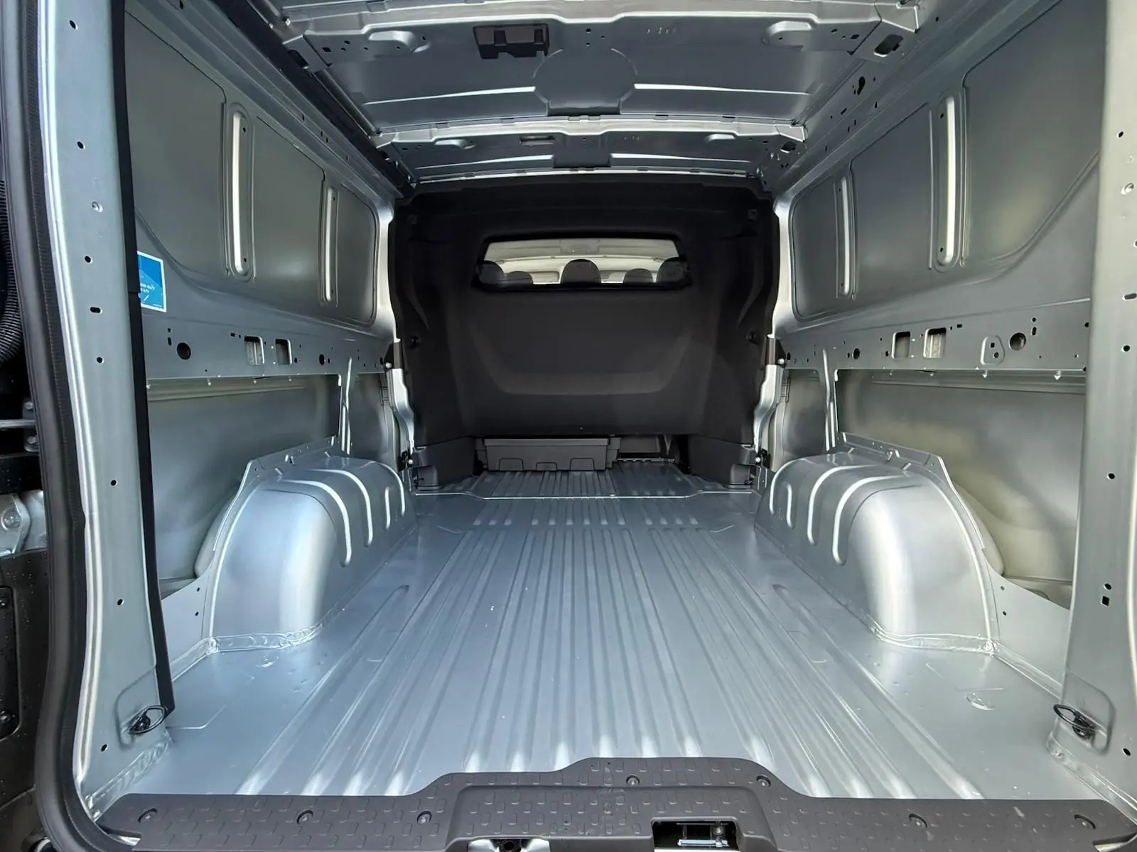 Vue rapprochée du volant noir et du tableau de bord du Renault Trafic cabine approfondie gris Highland, avec levier de vitesses manuel visible.