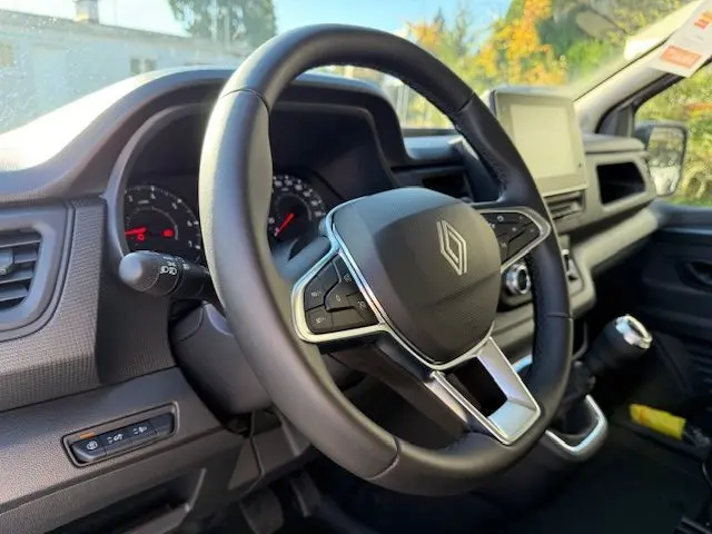 Vue 3/4 avant droit d'un Renault Trafic cabine approfondie gris Highland avec calandre noire et phares LED modernes.