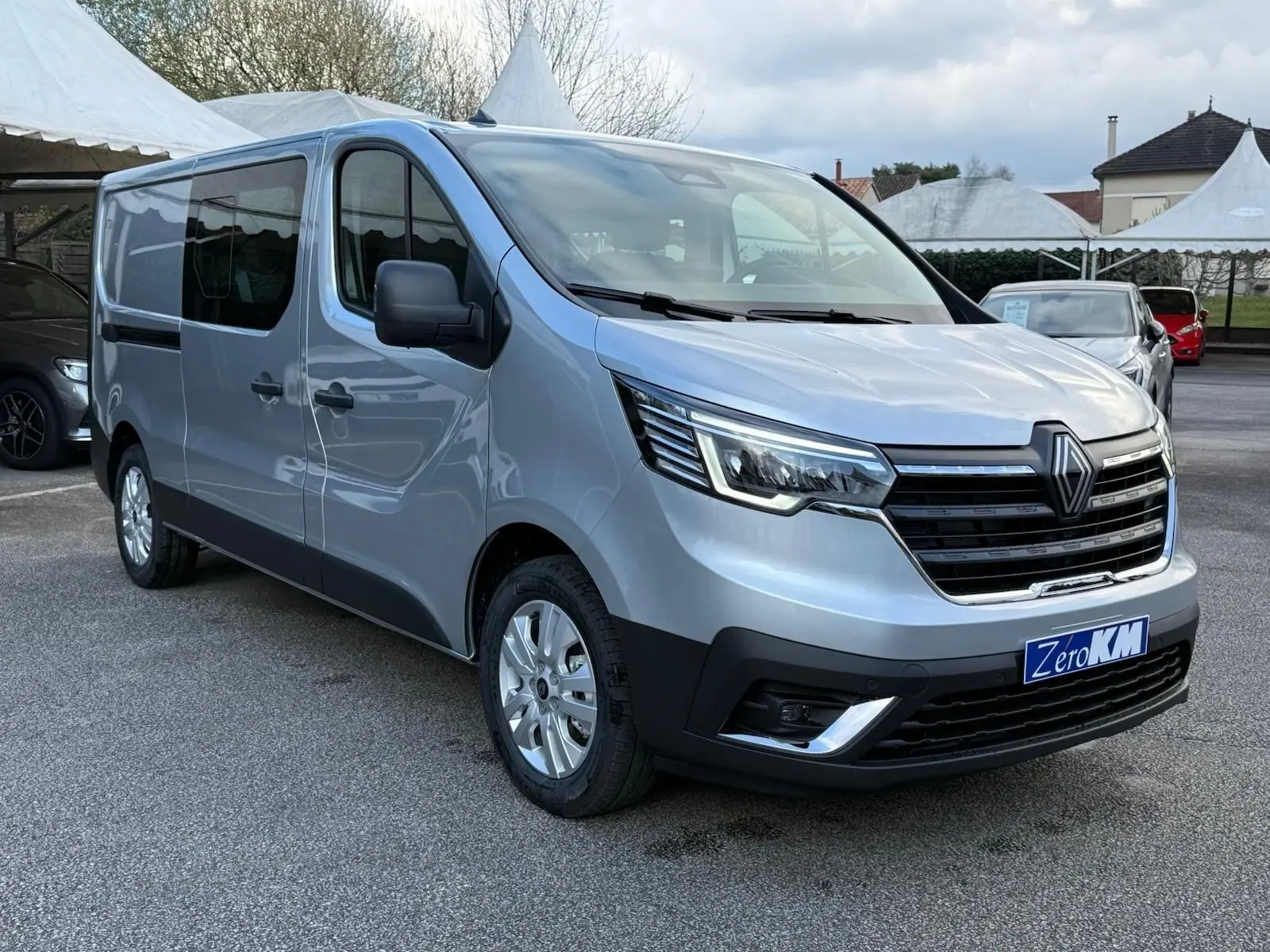 Vue 3/4 avant droit d'un Renault Trafic cabine approfondie gris Highland avec calandre noire et jantes argentées.