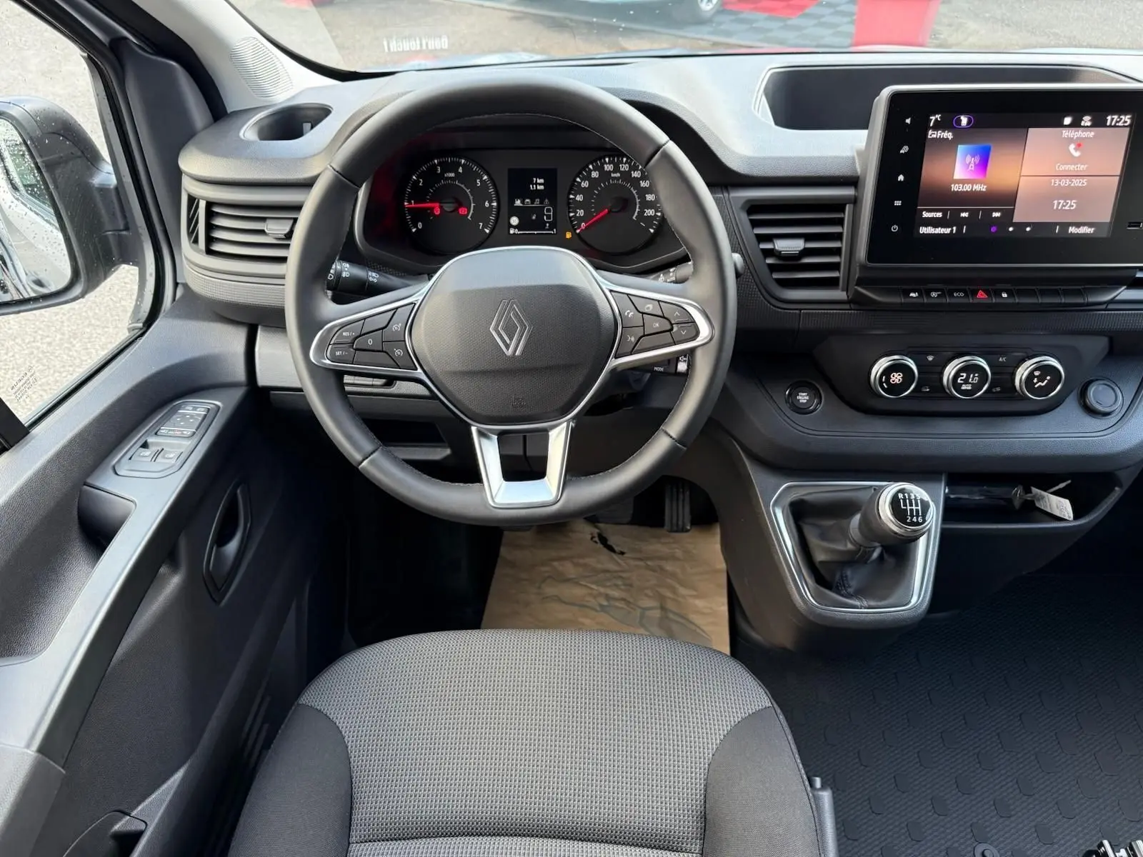 Gros plan sur le levier de vitesses manuel noir avec marquages blancs dans l'habitacle du Renault Trafic gris Highland.