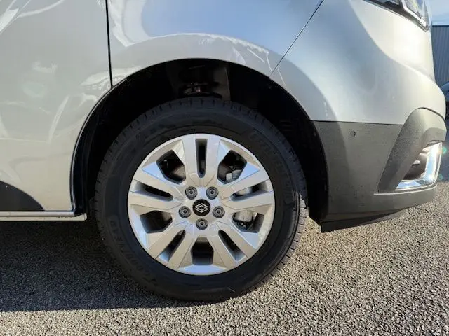 Gros plan sur les commandes de lève-vitres et réglage des rétroviseurs côté conducteur d'un Renault Trafic gris Highland.