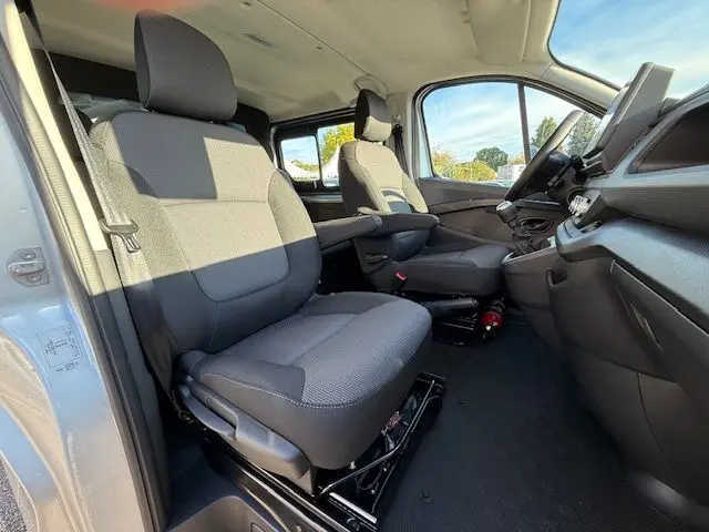 Intérieur avant du Renault Trafic cabine approfondie 2025, vue du poste de conduite avec tableau de bord et sièges gris.