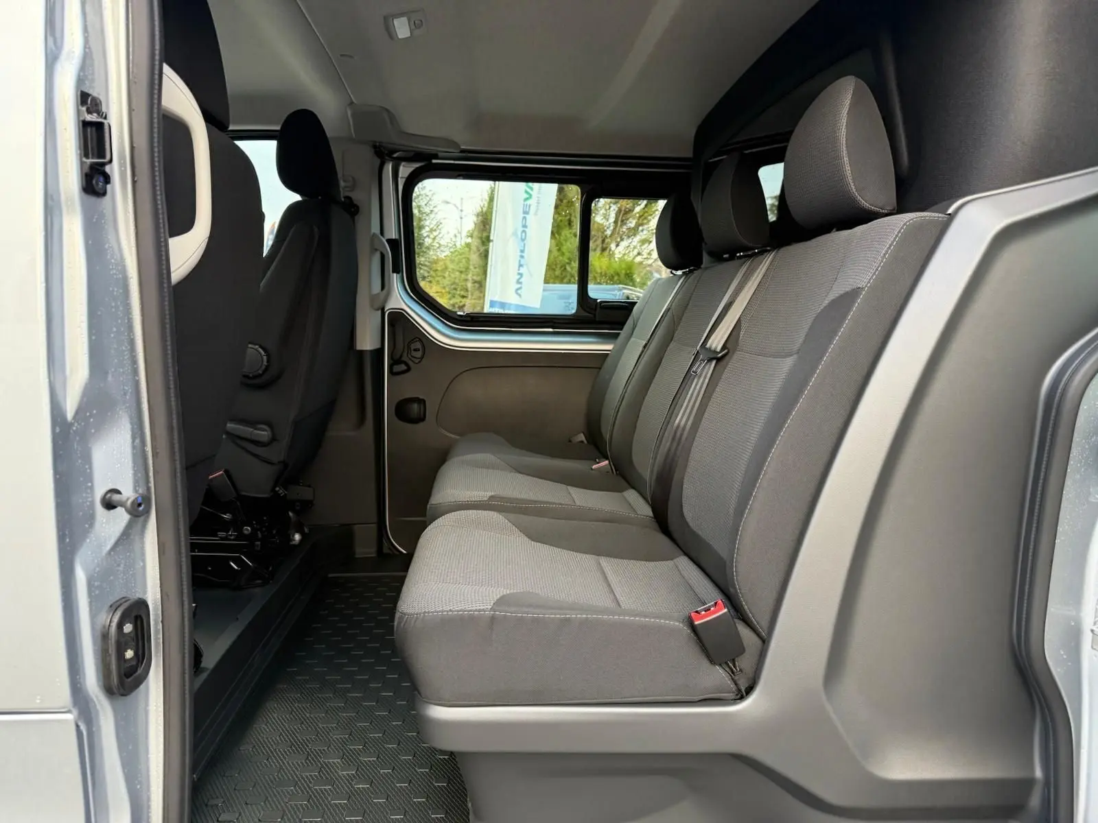 Vue latérale intérieure montrant la banquette arrière grise du Renault Trafic Cabine Approfondie L2H1 2025 avec porte ouverte.
