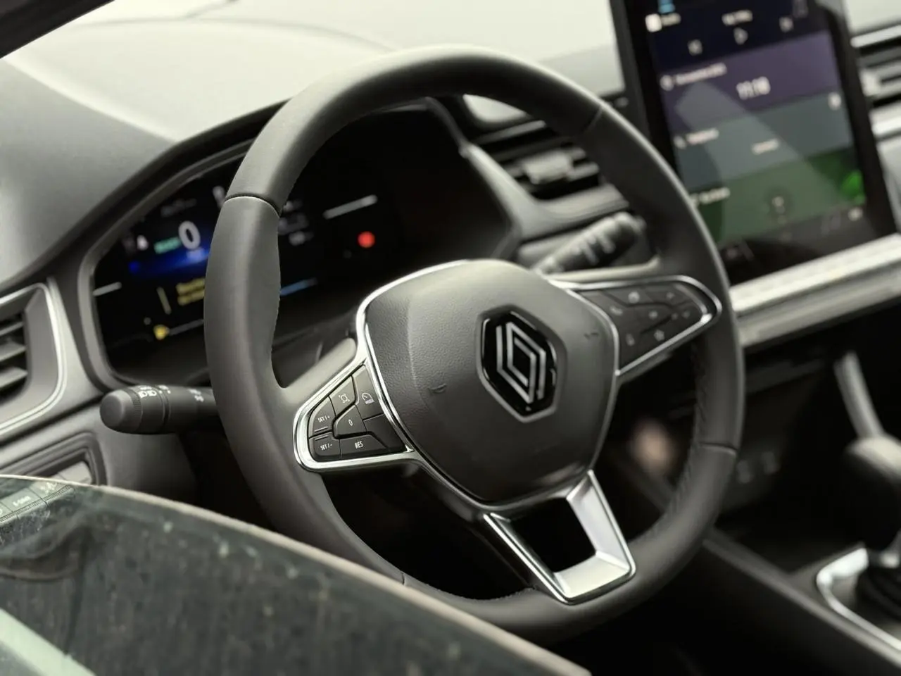 Volant noir avec logo Renault au centre, tableau de bord numérique et écran tactile dans l'habitacle du Renault Captur 2025.